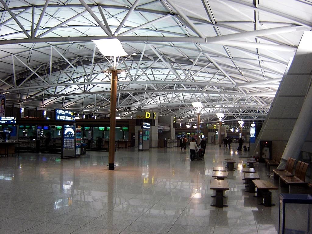 A departures hall at Incheon airport with check-in counters, steel roof trusses and benches