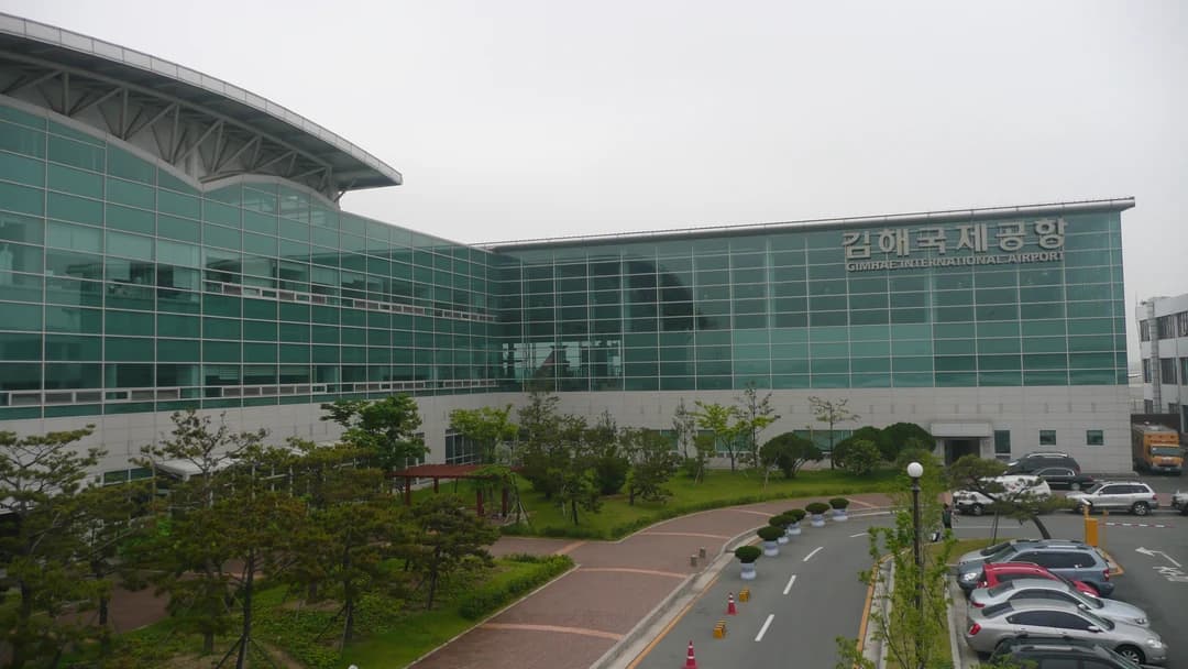 The glass-fronted terminal of Gimhae International Airport in Busan under a pale sky